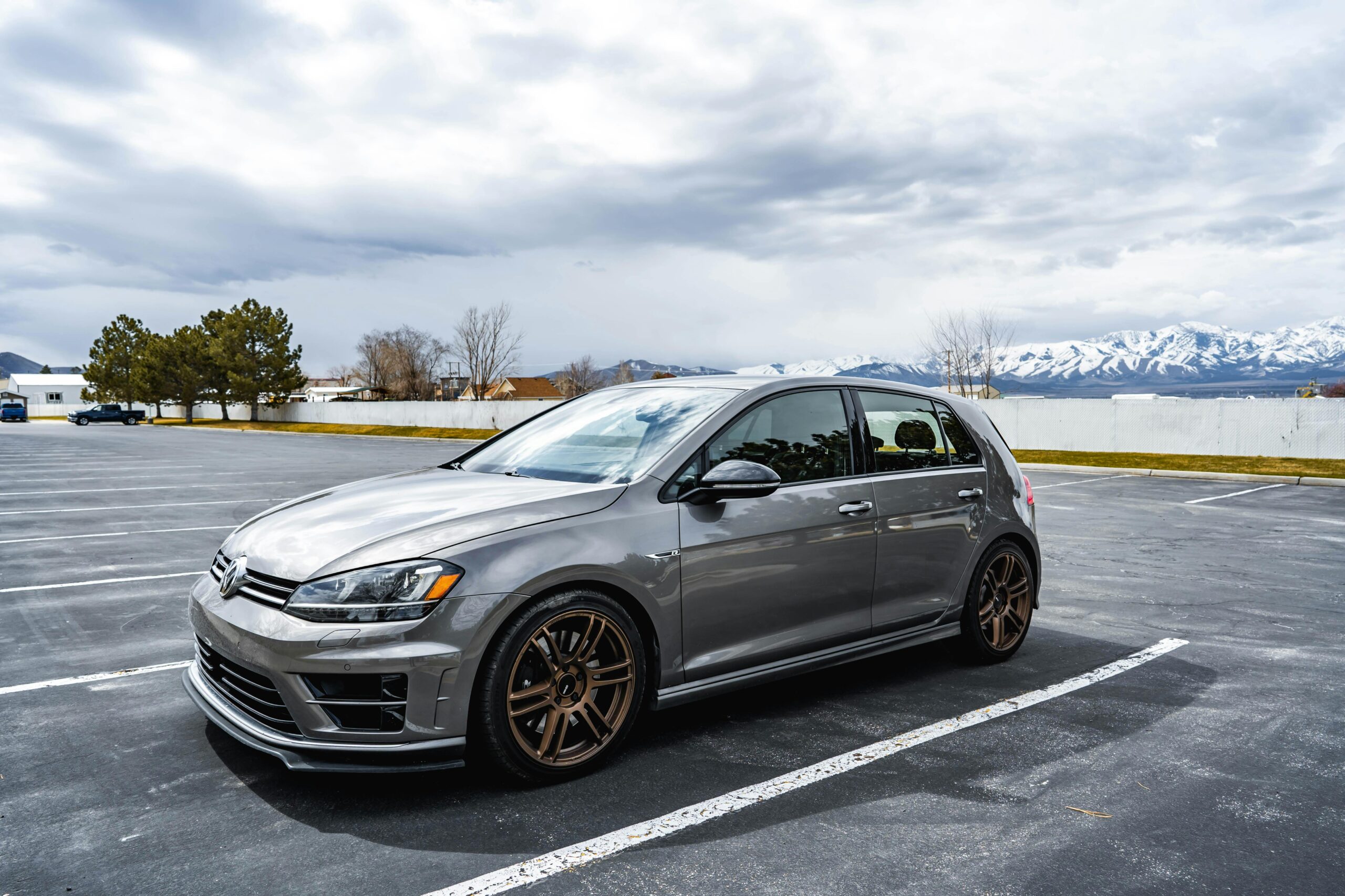 A sleek gray Volkswagen Golf parked in an open lot with mountain views.